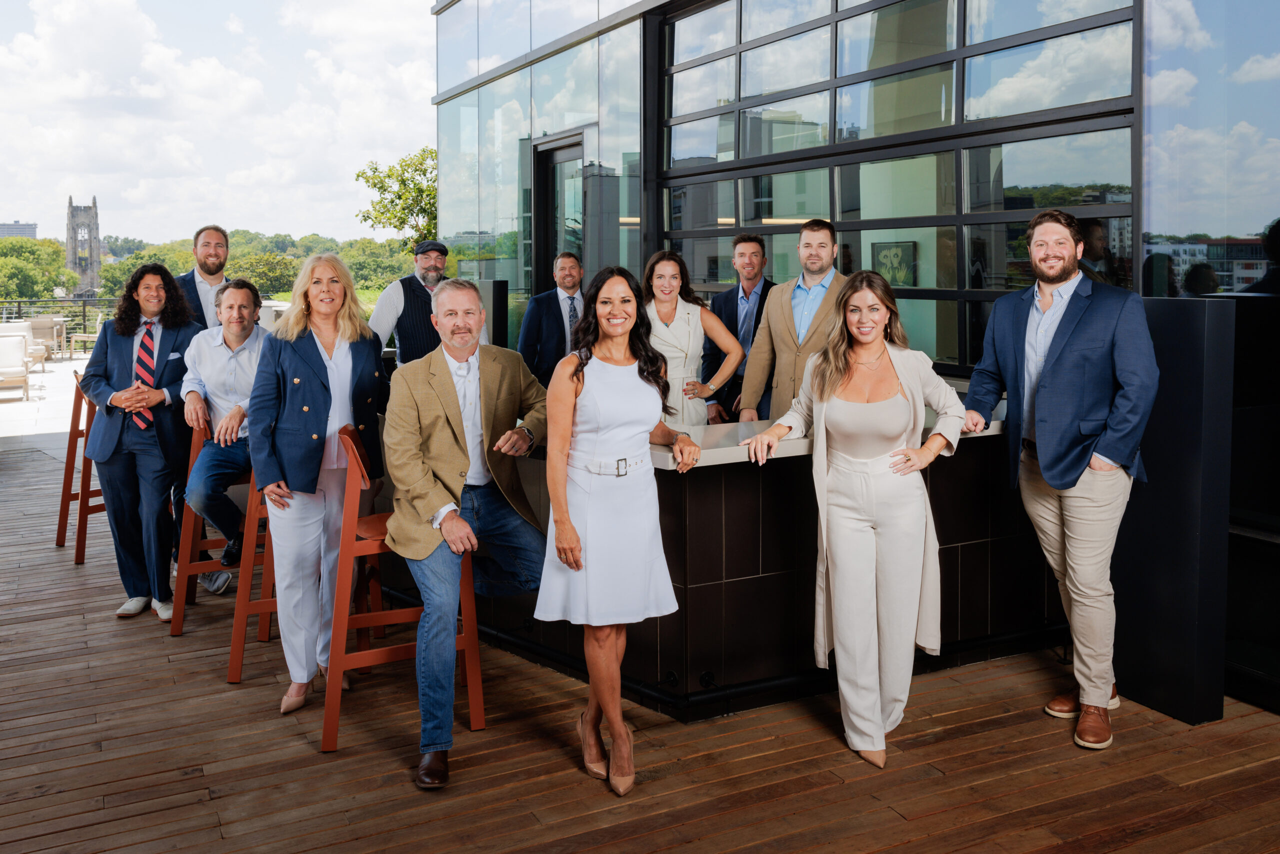 A team of experienced Nashville realtors posing on a modern rooftop terrace—supporting clients relocating to Nashville from California, guiding first-time buyers through neighborhoods near East Nashville and Belle Meade, and offering expertise in private estate homes near Franklin, TN, luxury properties with acreage, and gated communities. Perfect for those researching the cost of living in Nashville vs Atlanta in 2025 or seeking the best suburbs for families relocating.